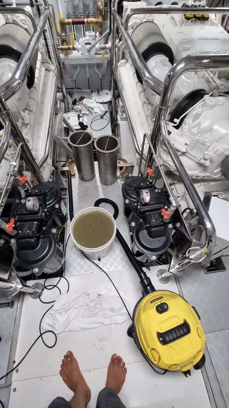 Engine room during a seawater-system flush, with a bucket of water beside the pumps.
