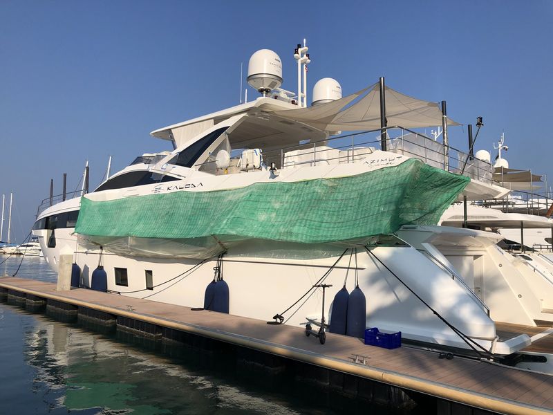 The yacht alongside under scaffold mesh and plastic sheeting for exterior paint work